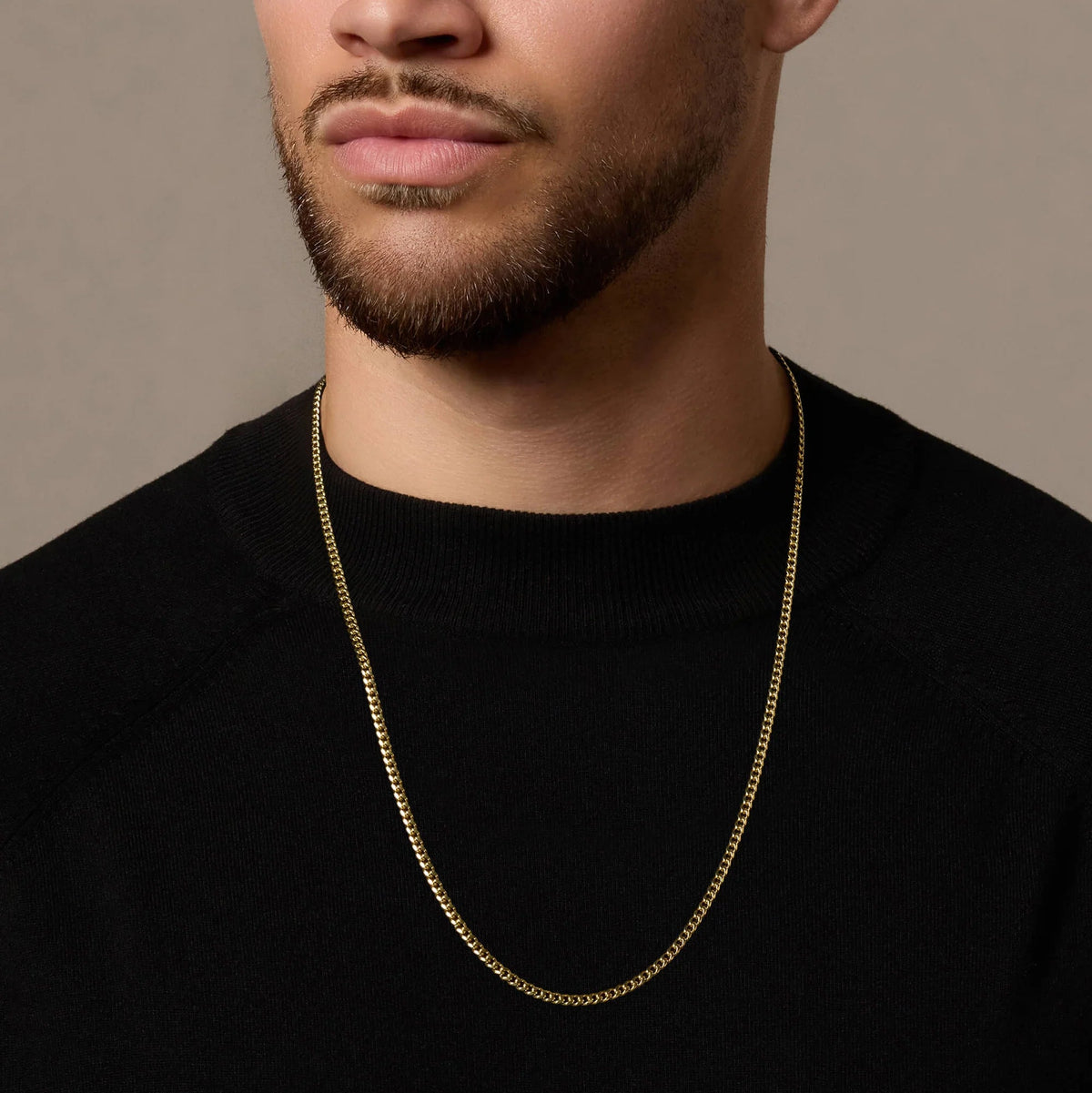 Man wearing a gold chain necklace against a neutral background