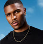 A close-up portrait of a man wearing a delicate gold chain necklace over a black crewneck shirt, set against a bright blue sky background.