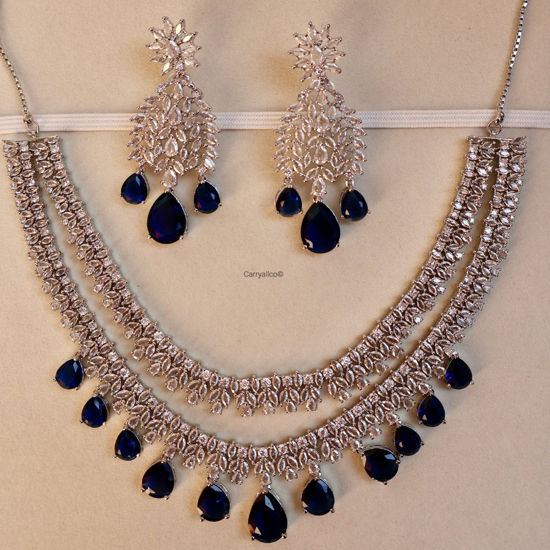 Silver necklace with blue stones and matching earrings on a beige background