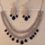 Silver necklace with blue stones and matching earrings on a beige background
