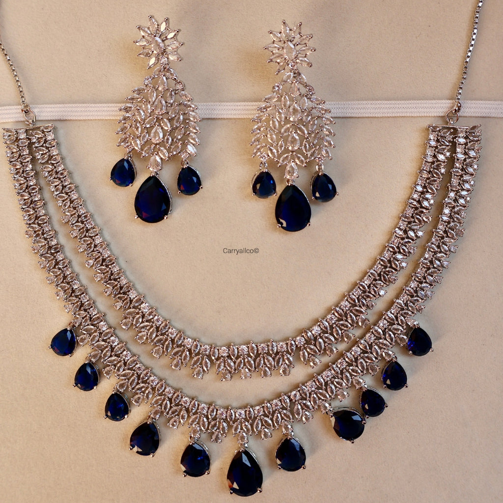 Silver necklace with blue stones and matching earrings on a beige background