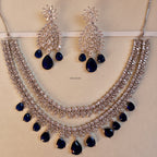 Silver necklace with blue stones and matching earrings on a beige background