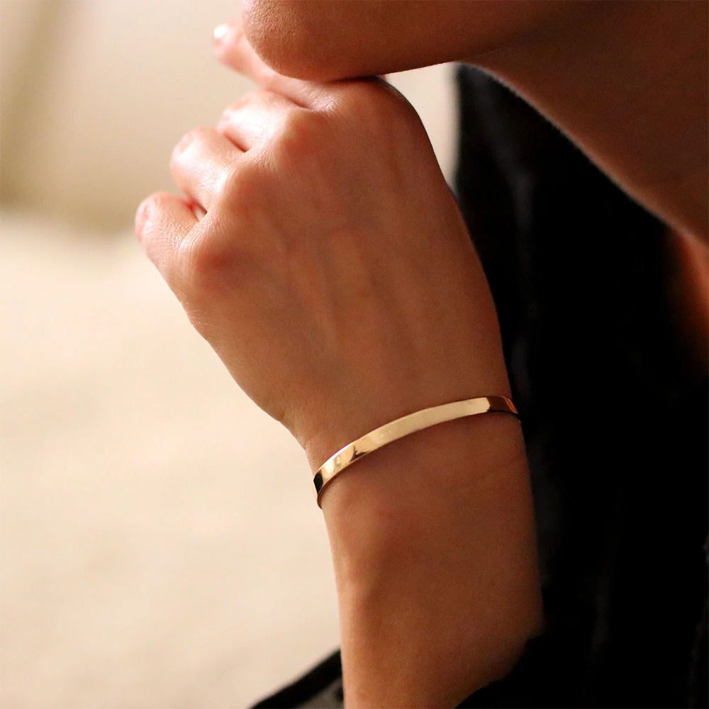 Gold bracelet on a wrist with a blurred background