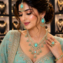 Woman wearing a turquoise and gold jewelry set in a jewelry store.