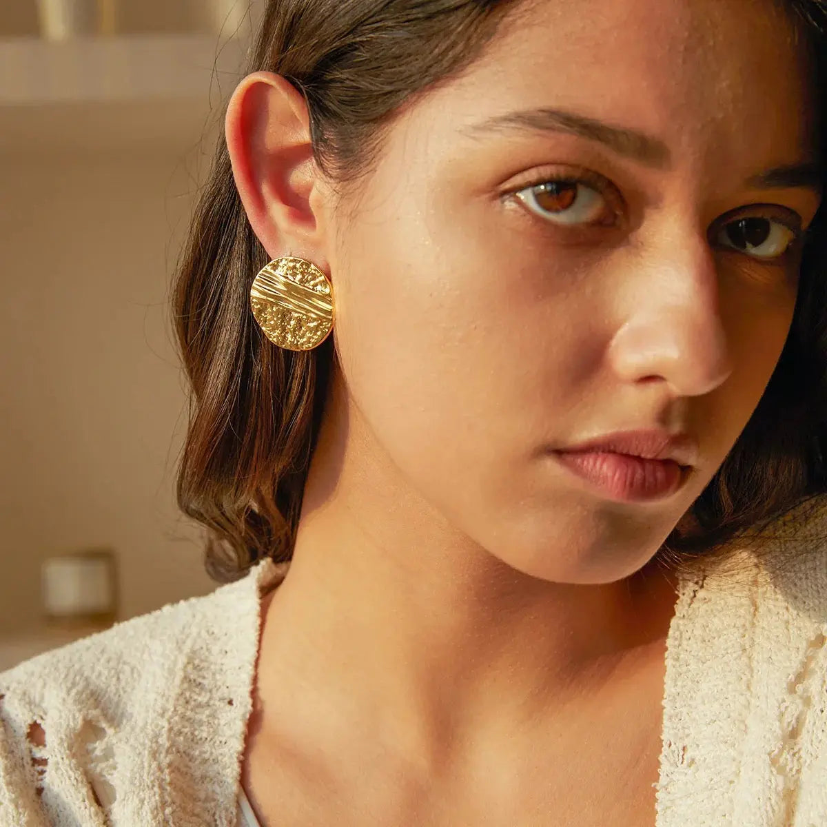 Close-up of a woman wearing gold earrings with a blurred background