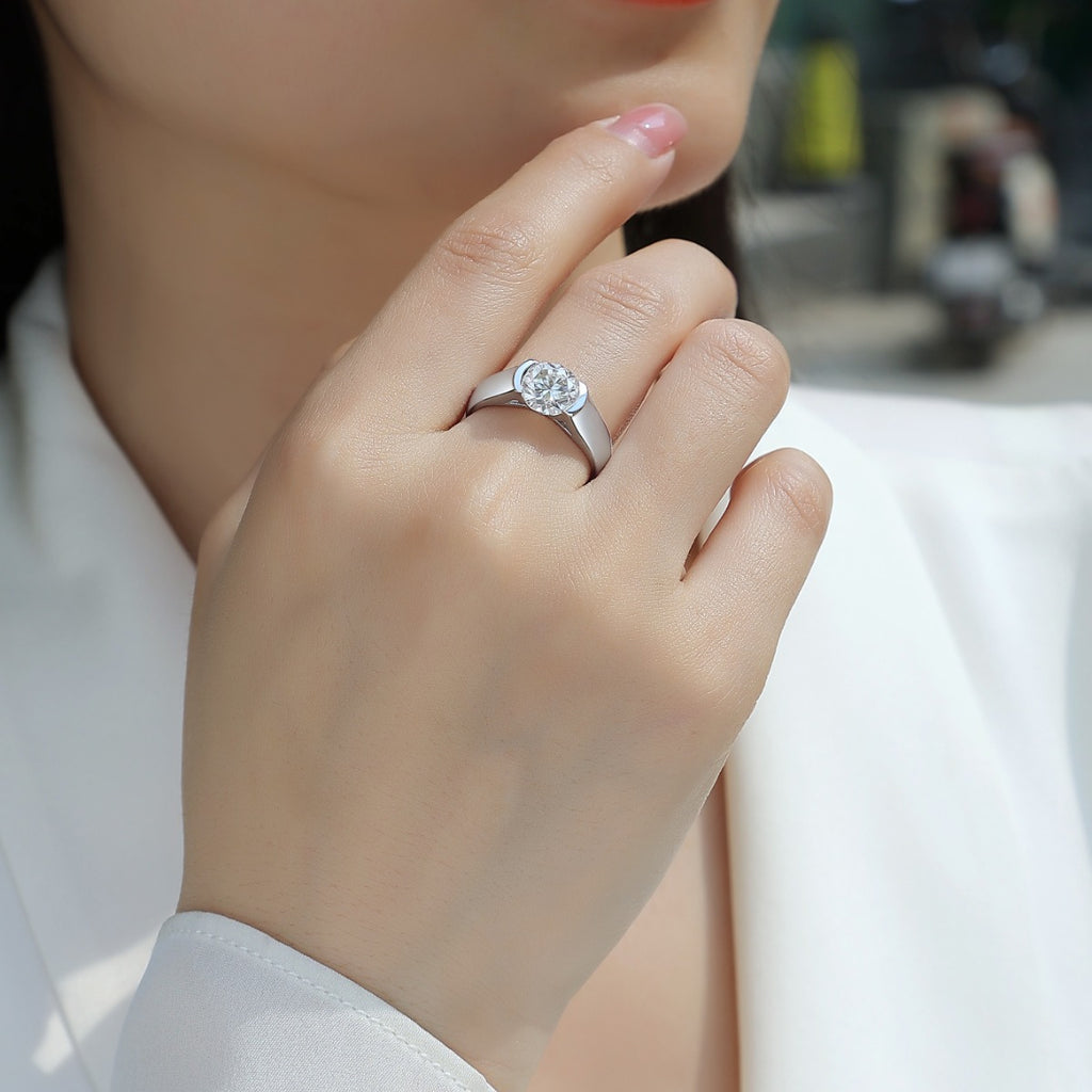 Hand wearing a silver ring with a diamond, blurred background