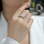 Hand wearing a silver ring with a diamond, blurred background