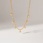 Gold necklace with small pearls on a light gray background