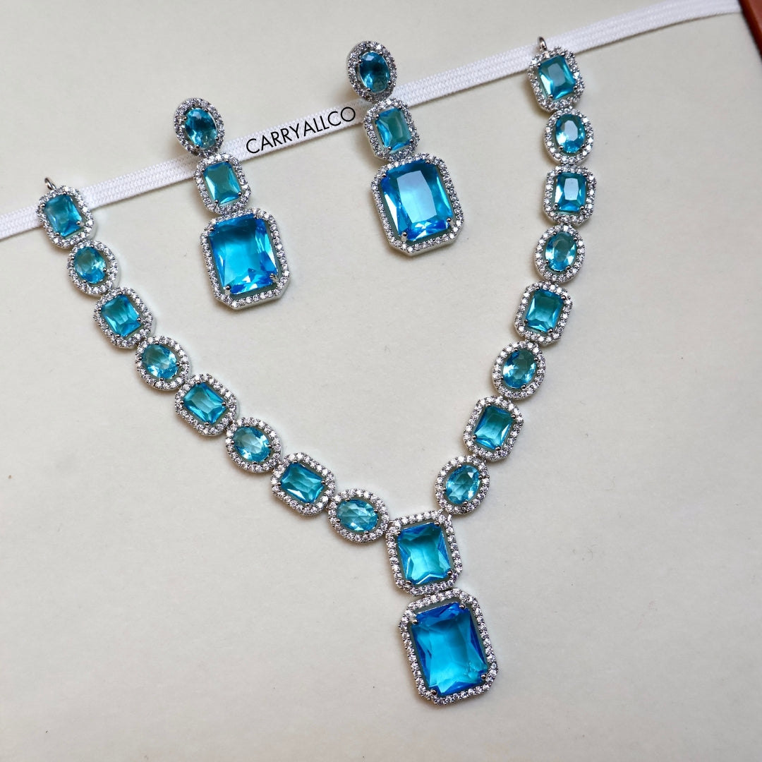 Necklace and earrings set with blue gemstones on a white background