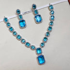 Necklace and earrings set with blue gemstones on a white background