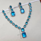Necklace and earrings with blue gemstones on a white background