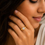 Close-up of a woman wearing a gold ring with a diamond on her hand.