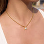 Gold necklace with a small pendant on a person's neck