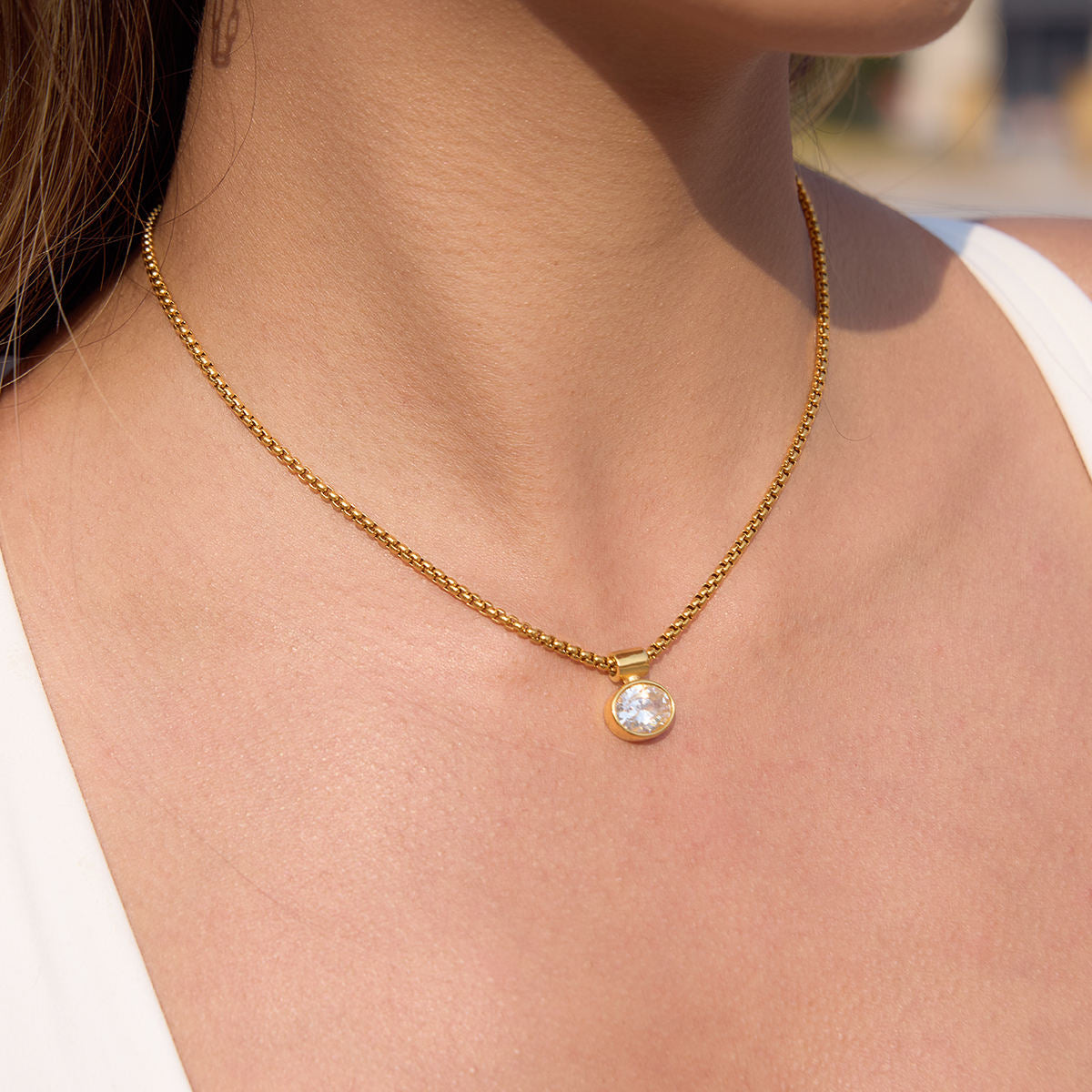 Gold necklace with a small pendant on a person's neck