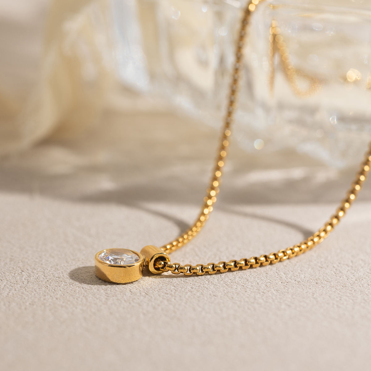 Gold necklace with a heart-shaped pendant on a soft beige background