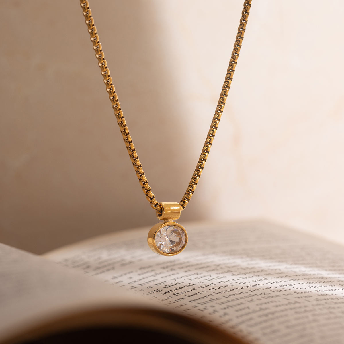 Gold necklace with a diamond pendant on an open book