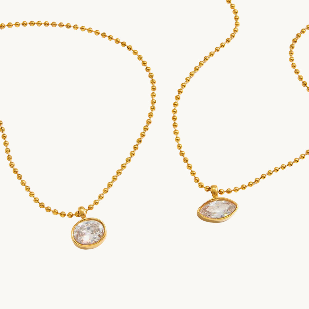 Two gold necklaces with round pendants on a white background