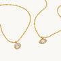 Two gold necklaces with round pendants on a white background
