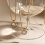 Gold necklaces with pendant stones on a glass stand