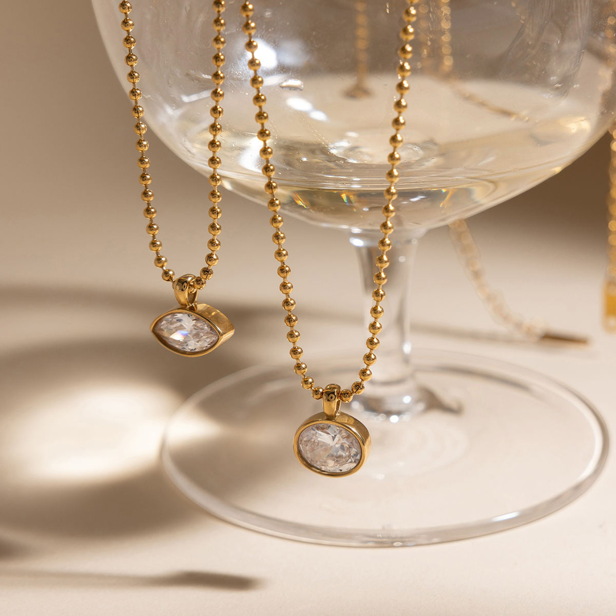 Gold necklaces with pendant stones on a glass stand