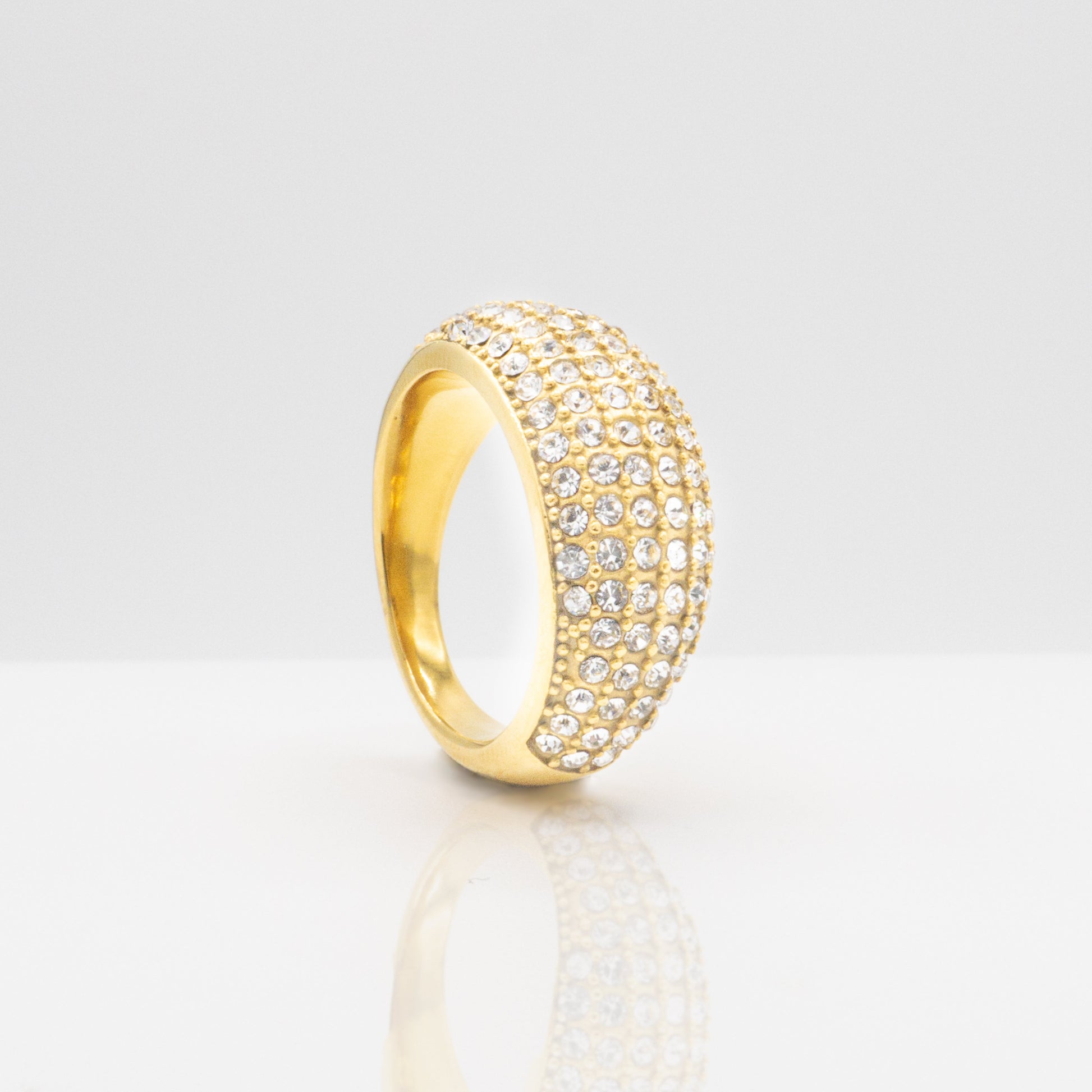 Gold ring with embedded stones on a light gray background