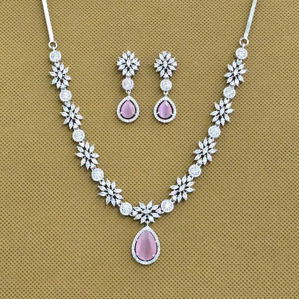 Jewelry set with necklace and earrings featuring pink stones on a brown background