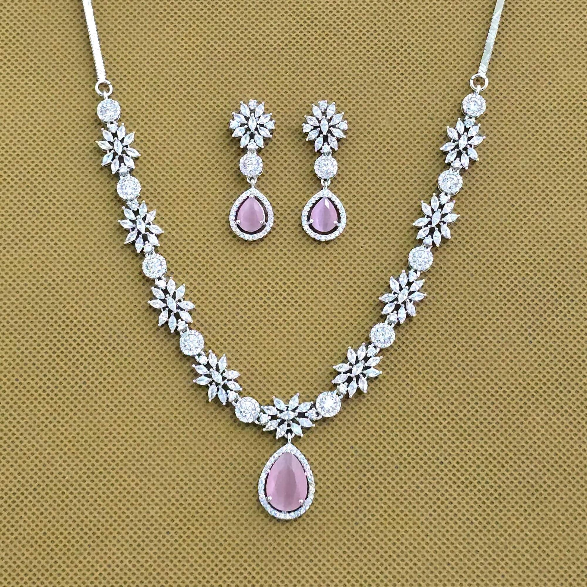 Jewelry set with necklace and earrings featuring pink stones on a brown background