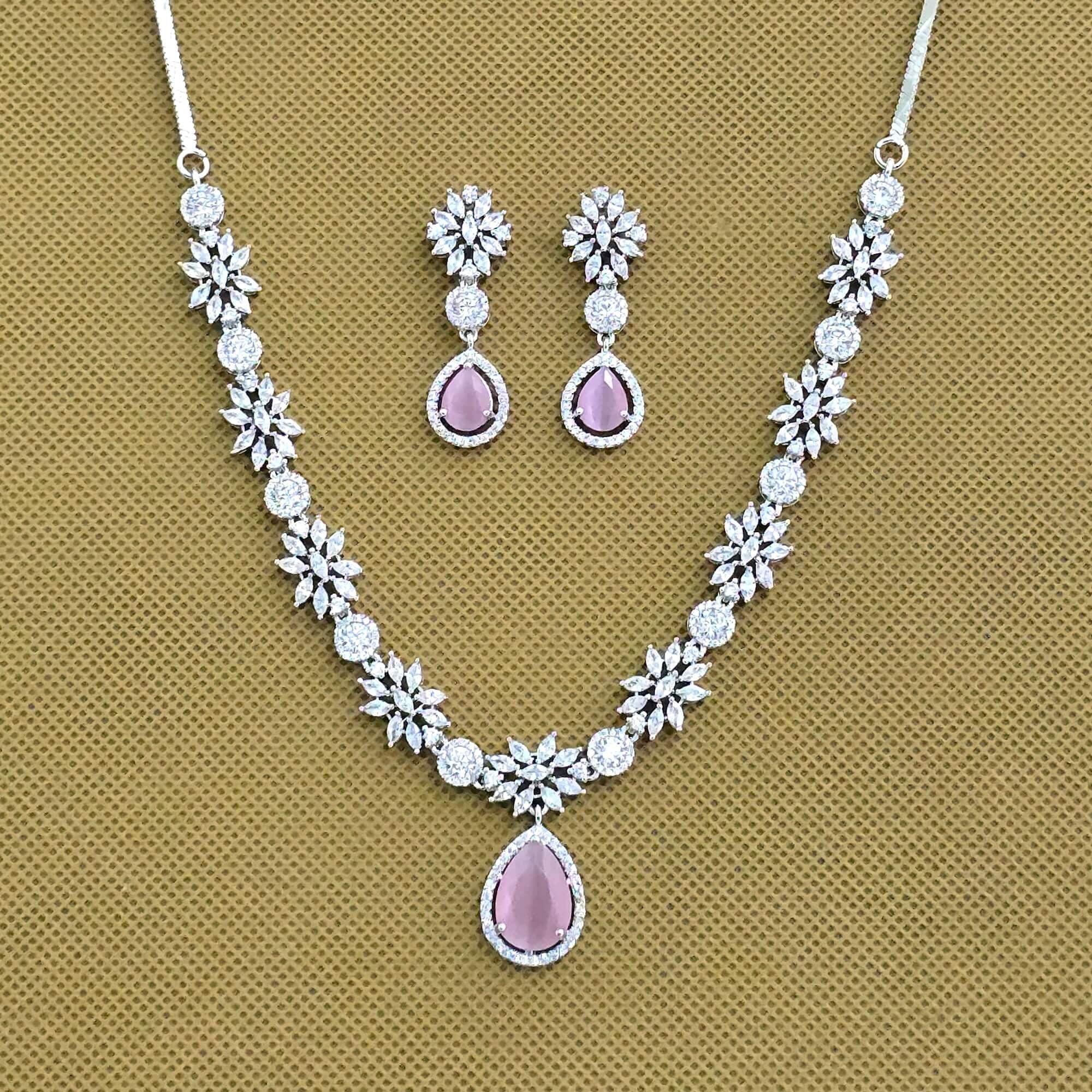 Jewelry set with necklace and earrings featuring pink stones on a brown background