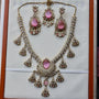Ornate necklace and earrings set with pink stones on a white background