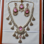 Ornate necklace and earrings set with pink stones on a white background