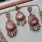 Pink teardrop earrings with gold and crystal details on a white surface