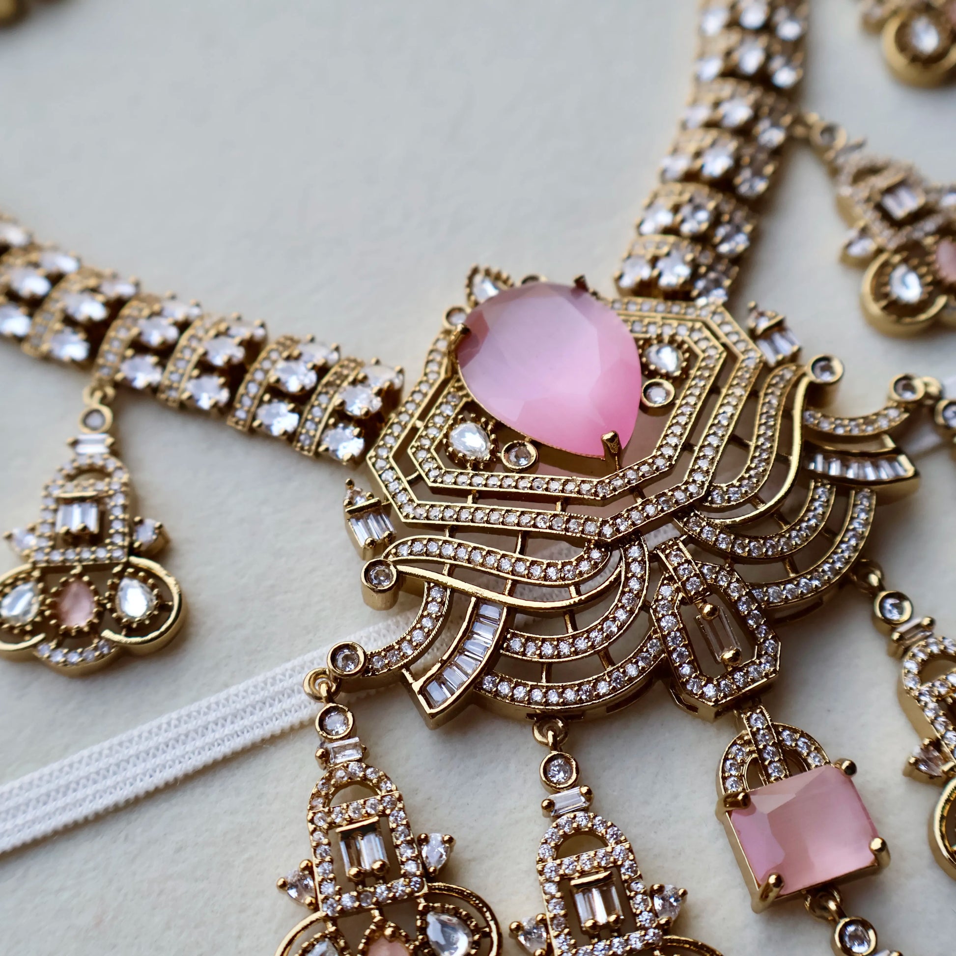 Ornate necklace with pink gemstones on a light background