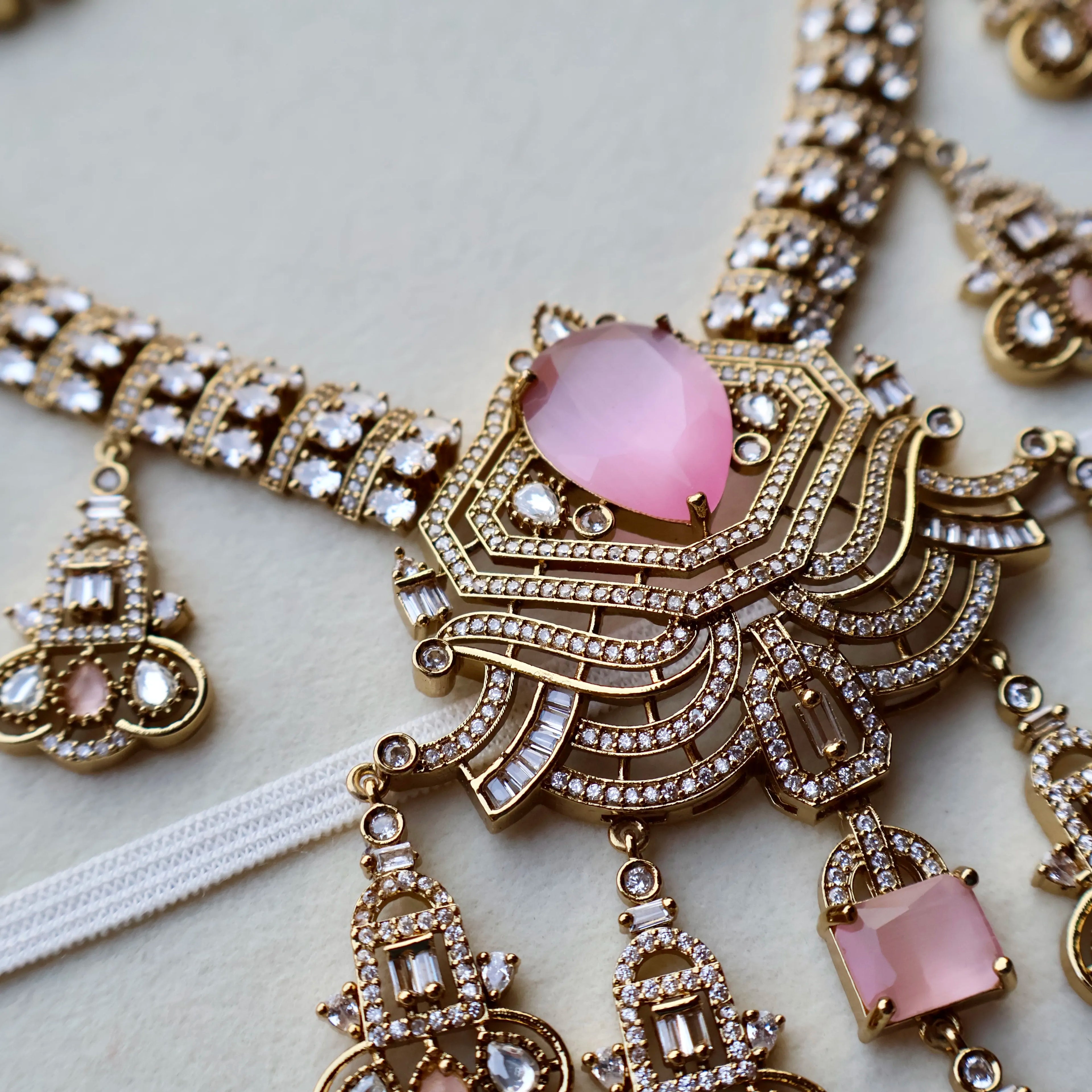 Ornate necklace with pink gemstones on a light background