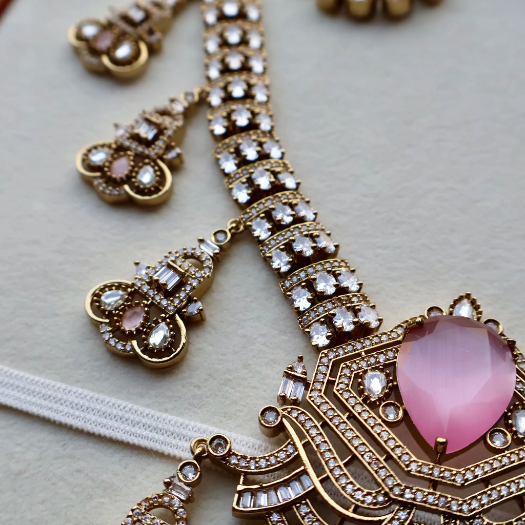Ornate necklace with pink heart pendant and gold accents on a light background