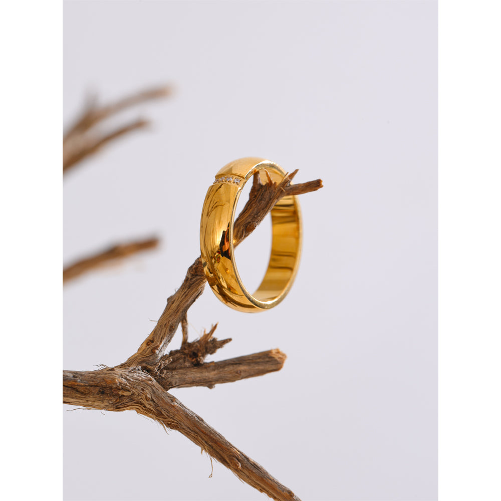 Gold ring on a branch with a light gray background