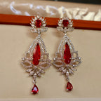 Pair of red gemstone earrings with silver accents on a beige background