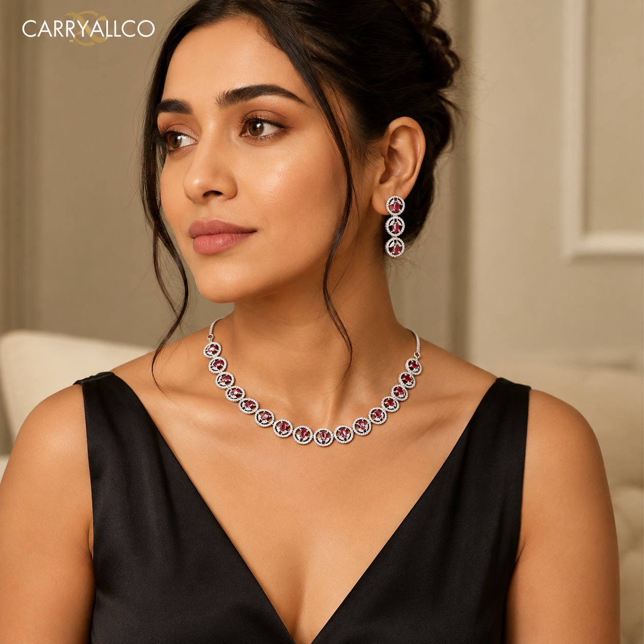 A woman wearing a silver-toned jewelry set from Carry All Co, featuring a delicate necklace and matching drop earrings with circular purple and white stones, set against a soft beige background.