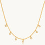 Gold necklace with small round pendants on a white background