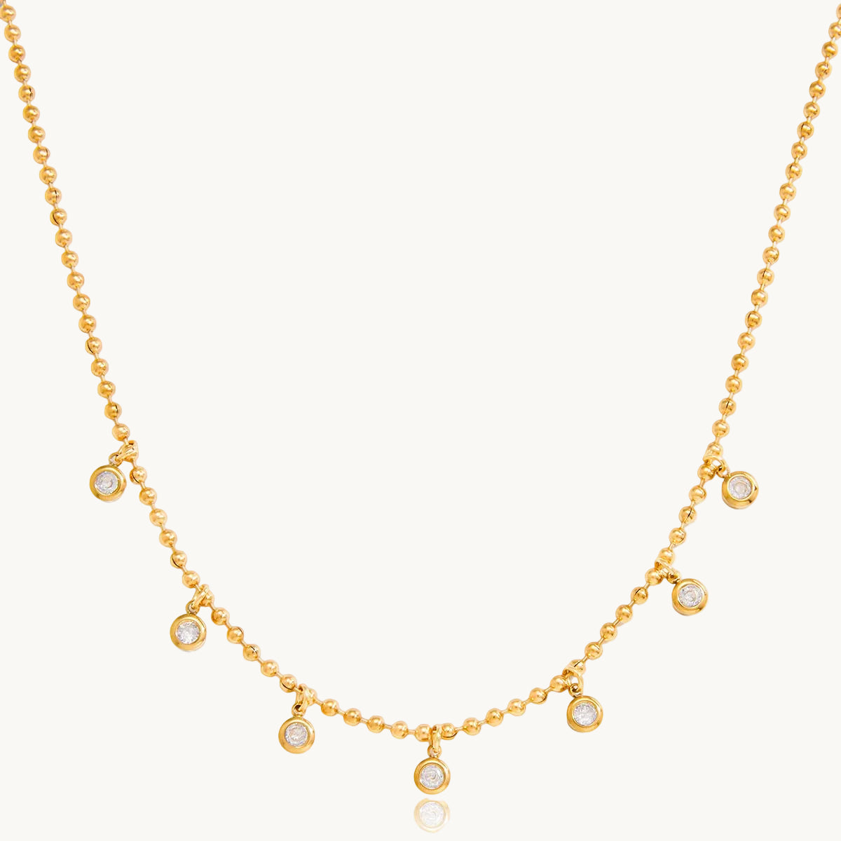 Gold necklace with small round pendants on a white background