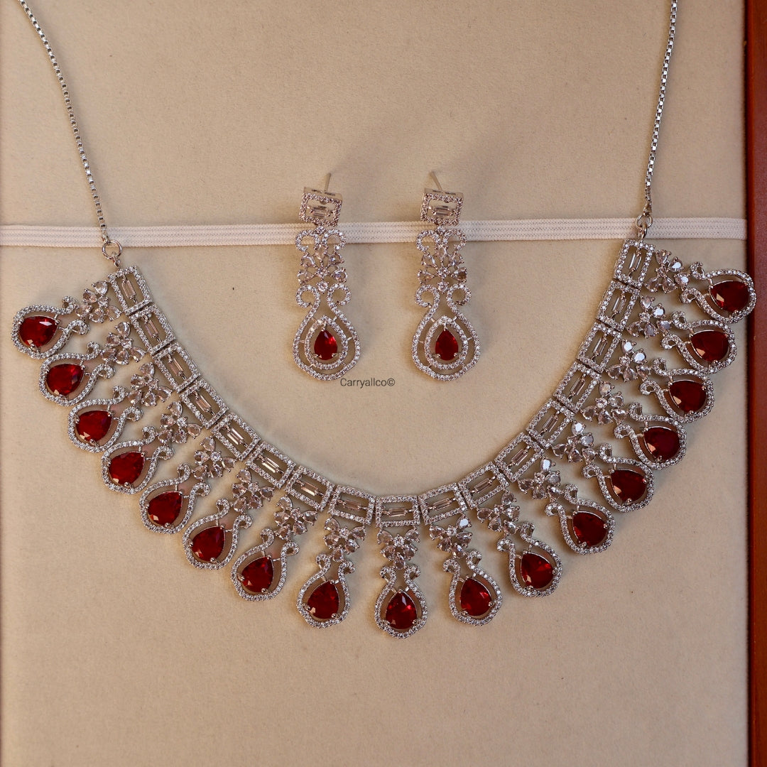 Jewelry set with necklace and earrings featuring red stones on a beige background