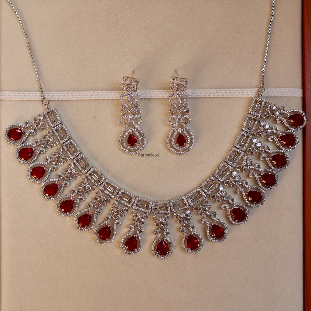 Jewelry set with necklace and earrings featuring red stones on a beige background