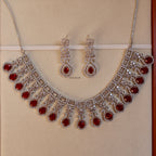 Jewelry set with necklace and earrings featuring red stones on a beige background