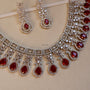 Jewelry set with necklace and earrings featuring red gemstones on a beige background