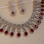Jewelry set with necklace and earrings featuring red gemstones on a beige background