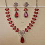 Red gemstone necklace and earrings on a beige background