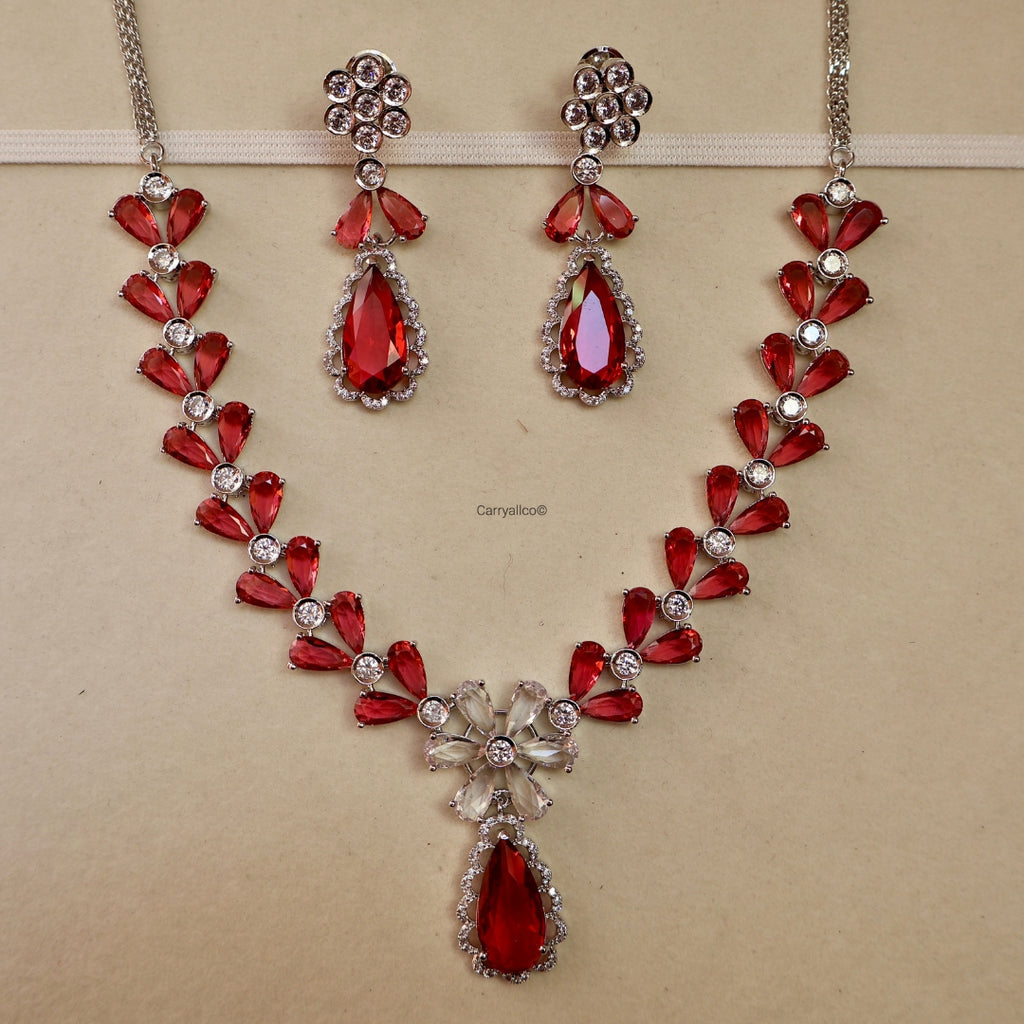 Red gemstone necklace and earrings on a beige background