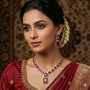 Woman wearing red and gold traditional attire with jewelry against a patterned background