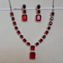 Jewelry set with red gemstones and silver accents on a beige background
