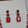 Red gemstone earrings with silver accents on a white background