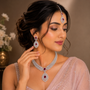 A woman wearing a matching silver-toned jewelry set with deep red stones, including a necklace, earrings, and a forehead ornament, styled with a light pink embroidered sari.